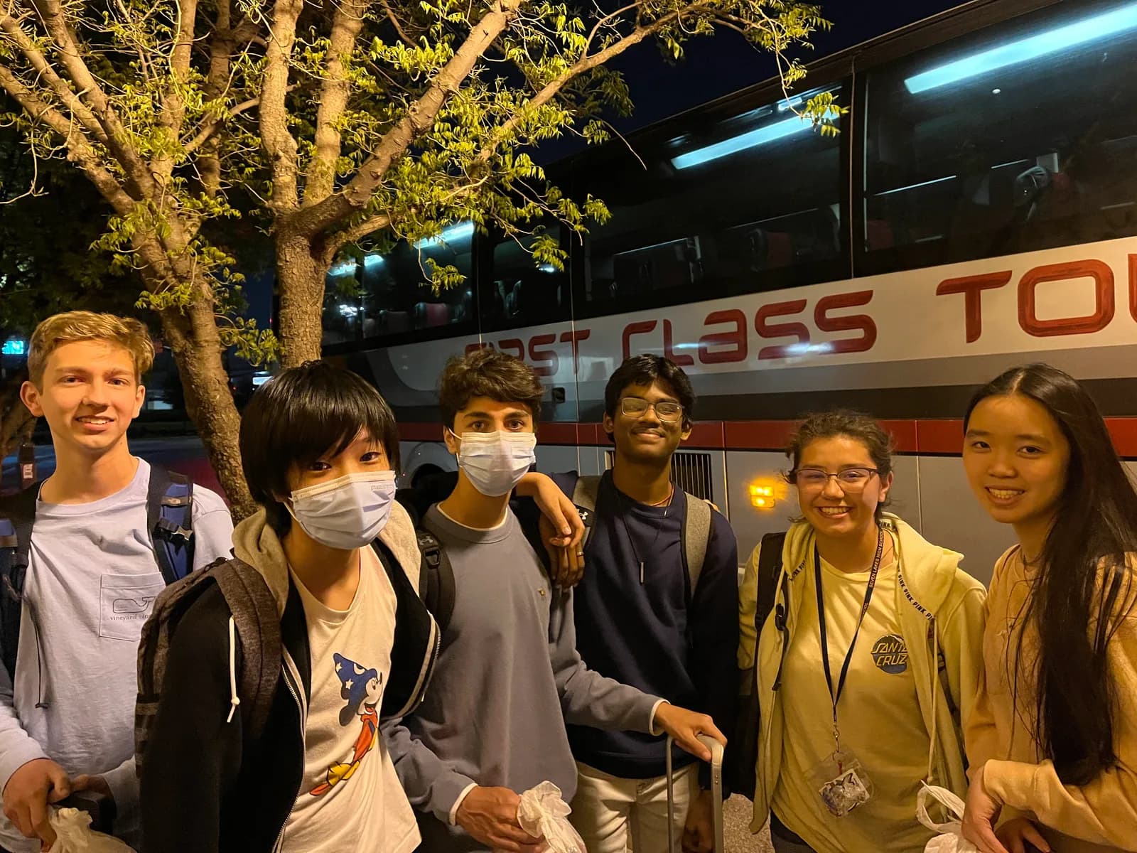 Members unloading by the charter bus at night