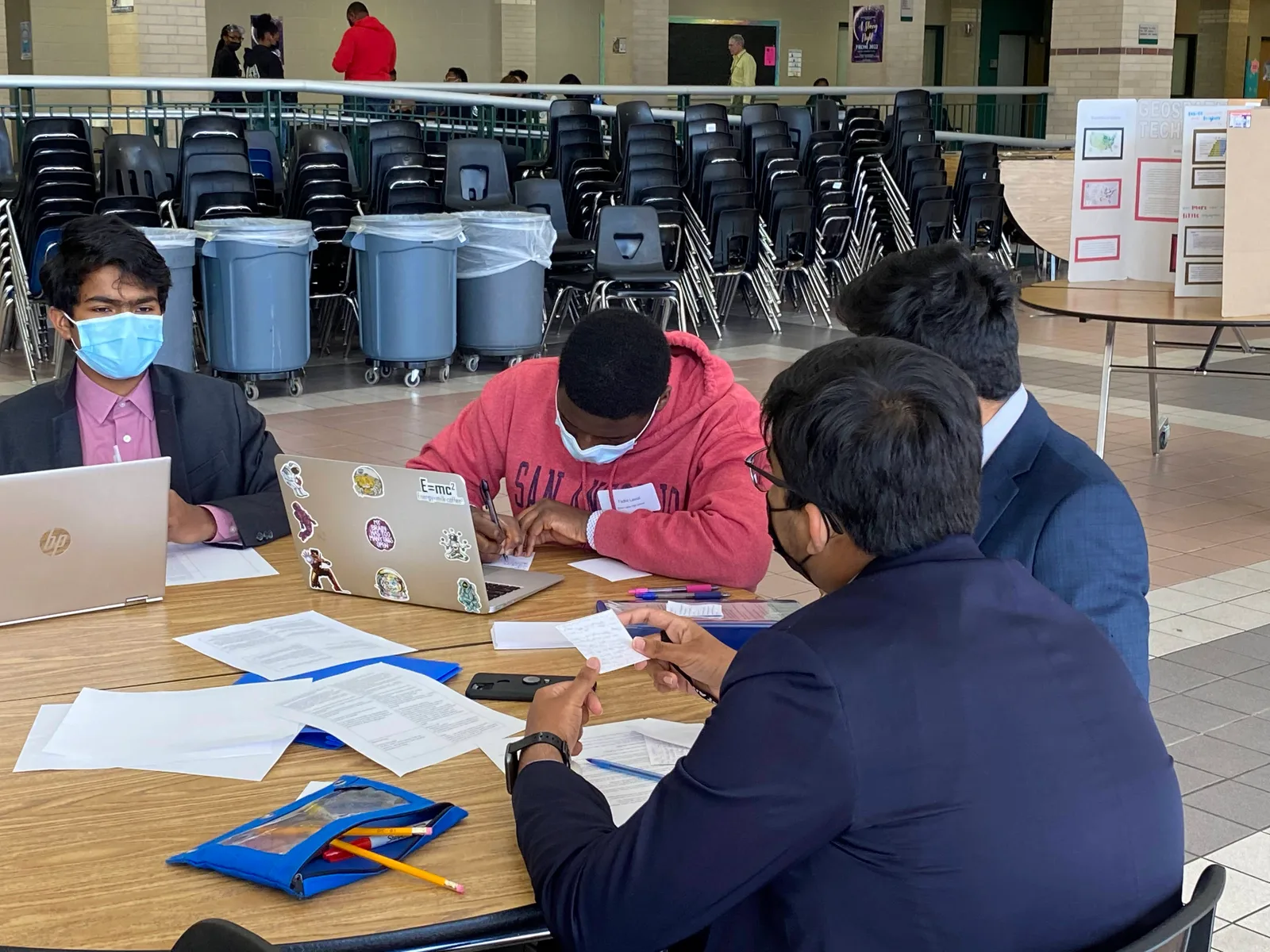 Members reviewing paperwork with laptops at a cafeteria table during Regionals