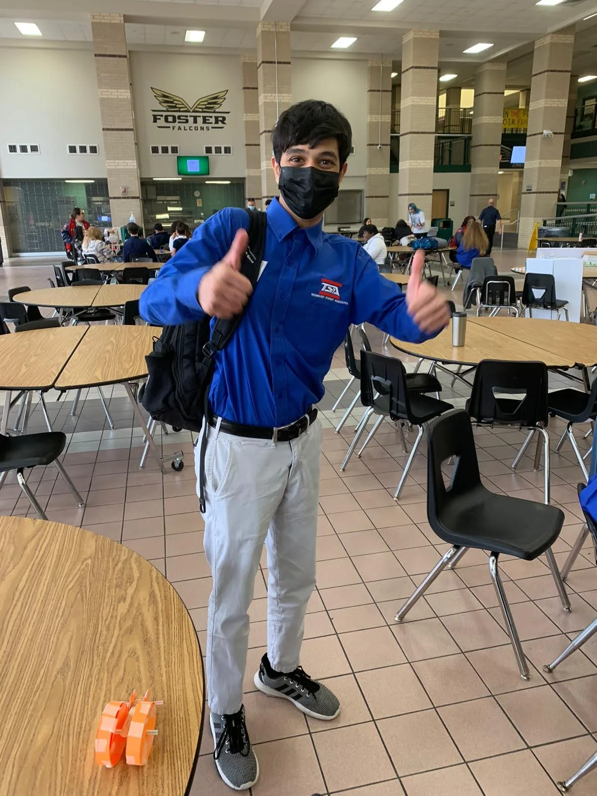 Member in blue TSA shirt giving two thumbs up in the cafeteria