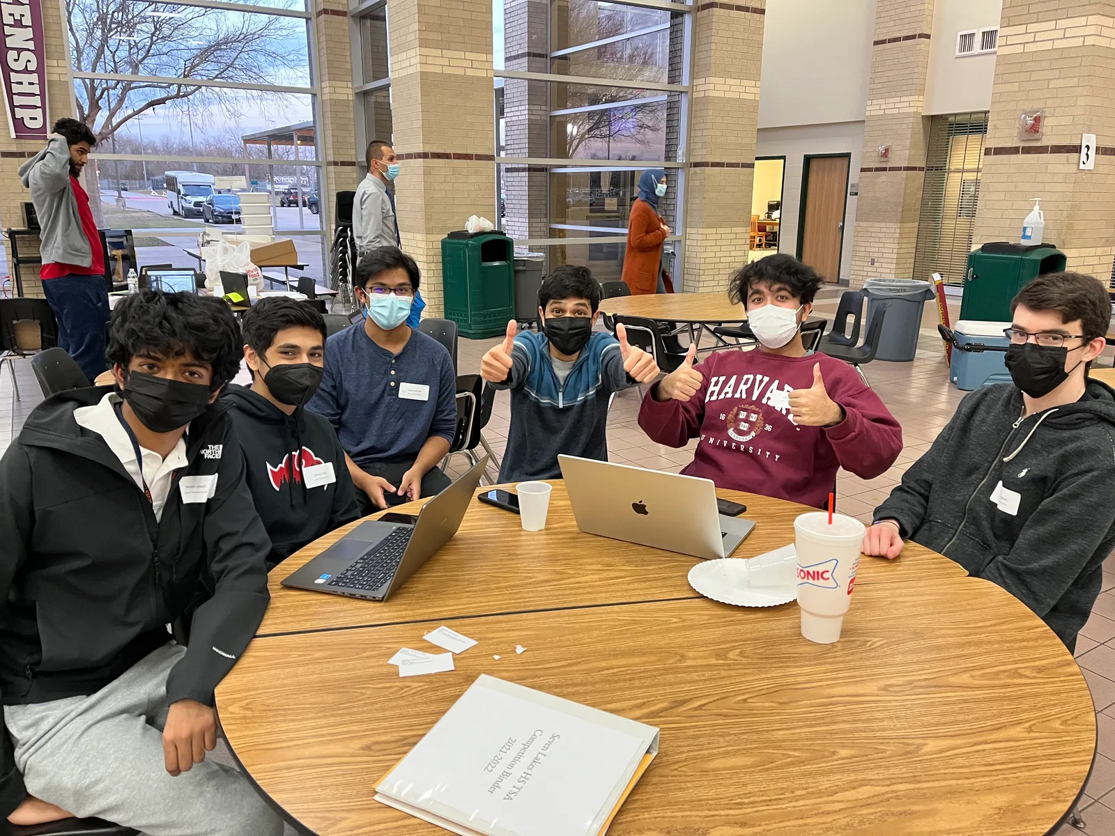 Members giving thumbs up behind their laptops