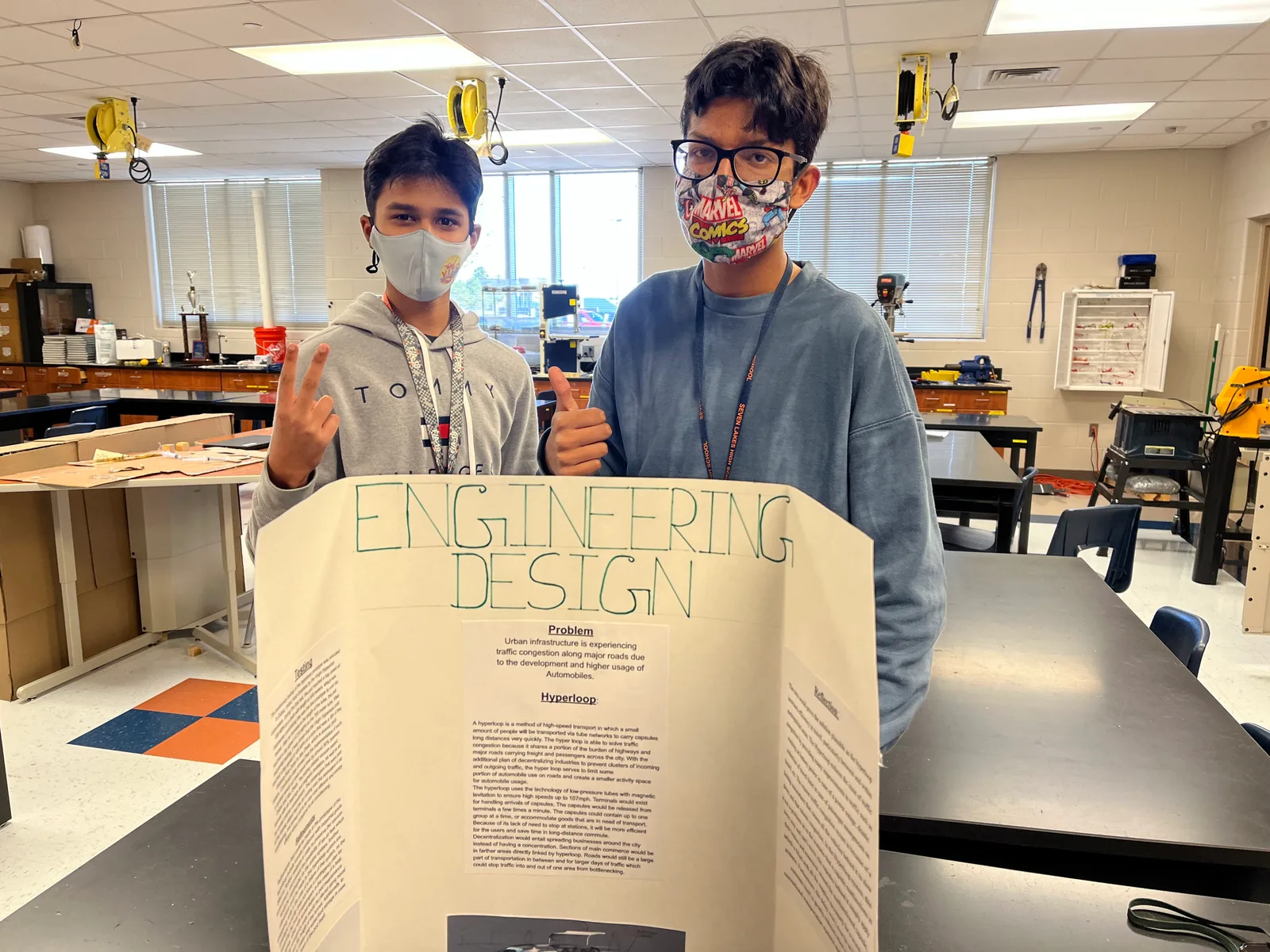 Two members presenting their Engineering Design tri-fold in the shop