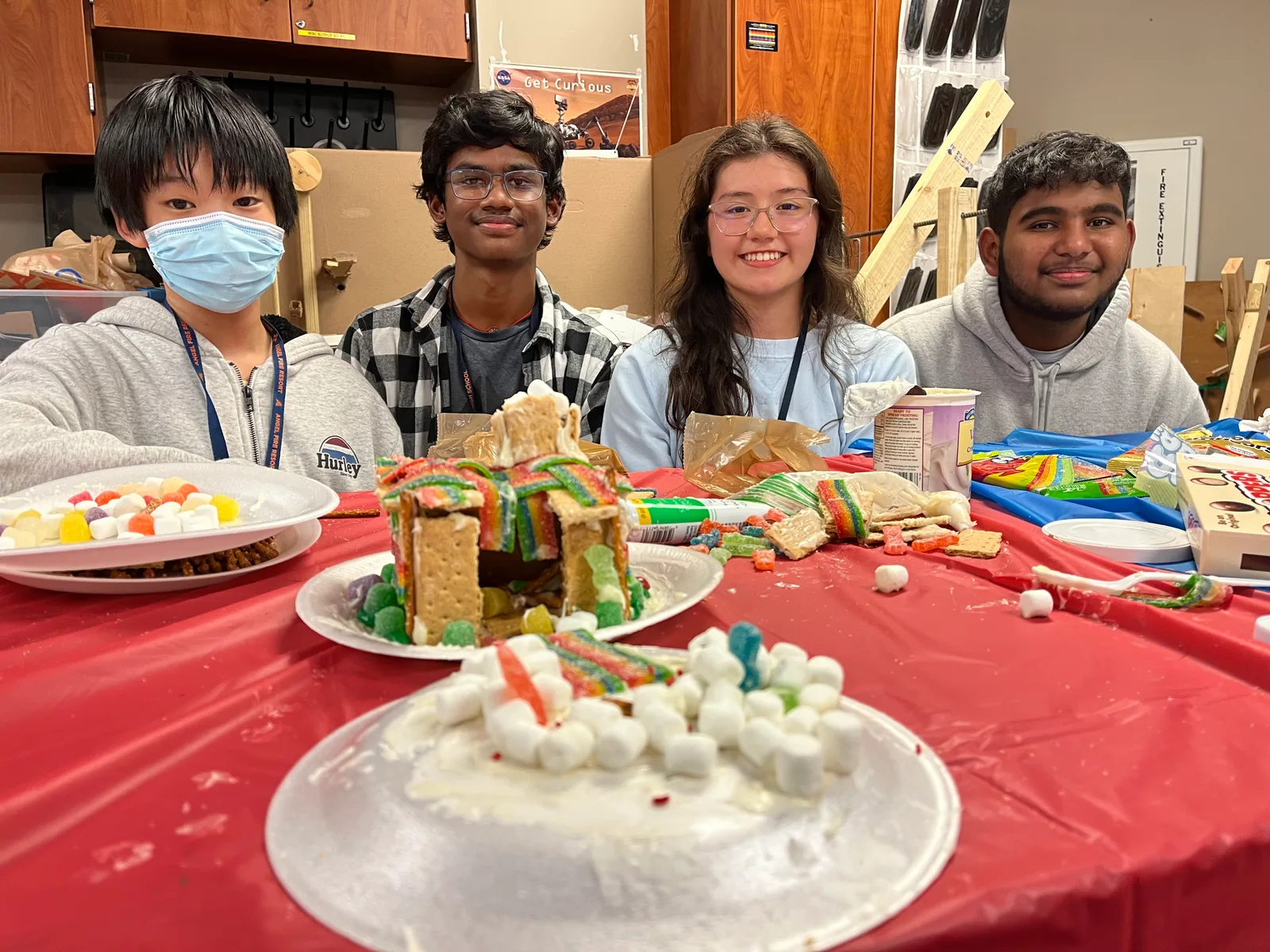 Members showing off graham-cracker builds at a red table