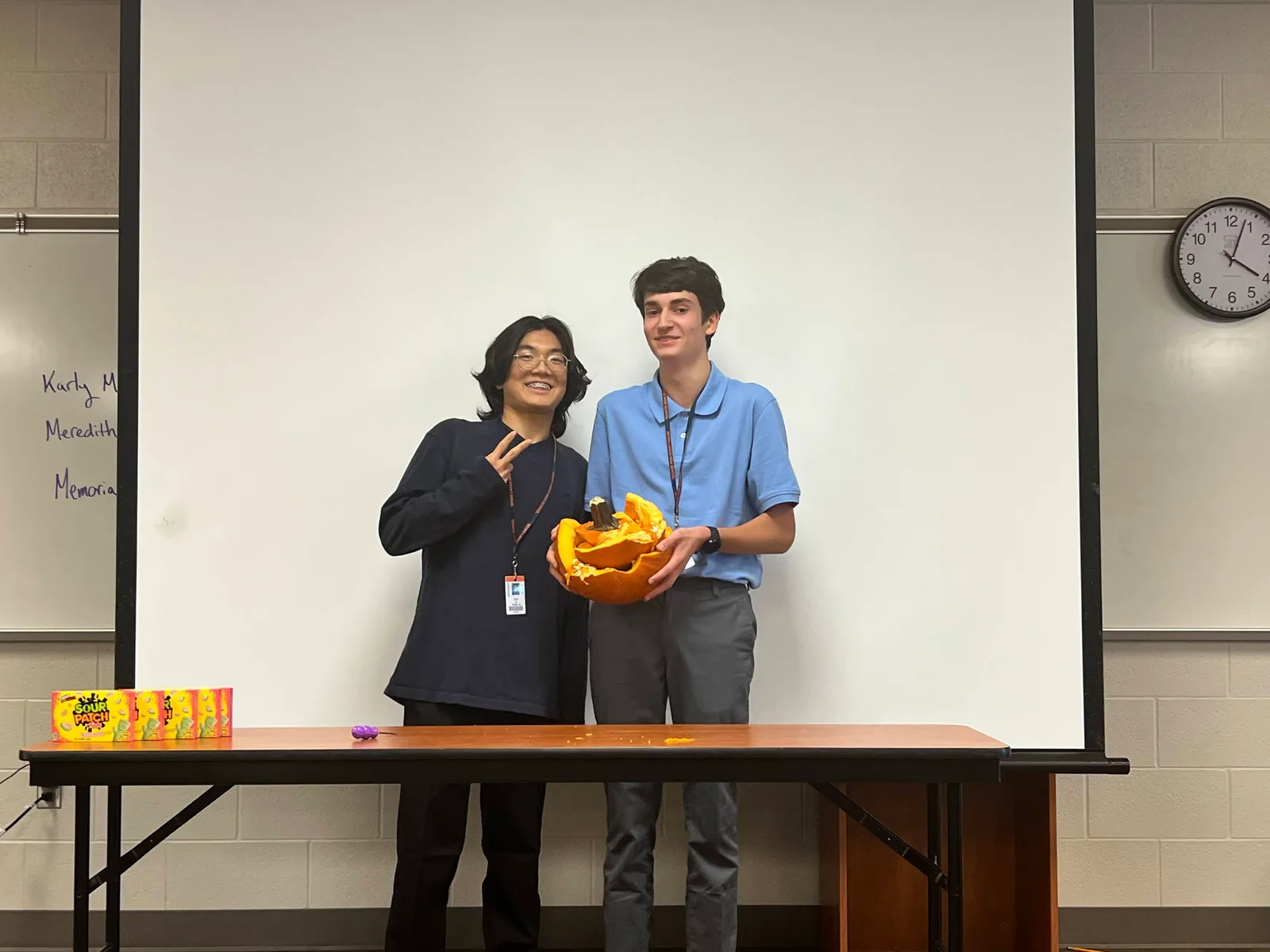 Two members showing off their carved pumpkin at the fall social
