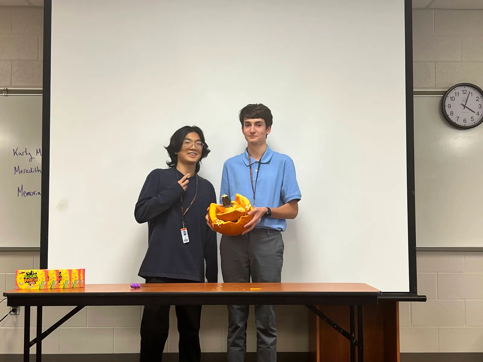 Members posing with their pumpkin, one flashing a peace sign