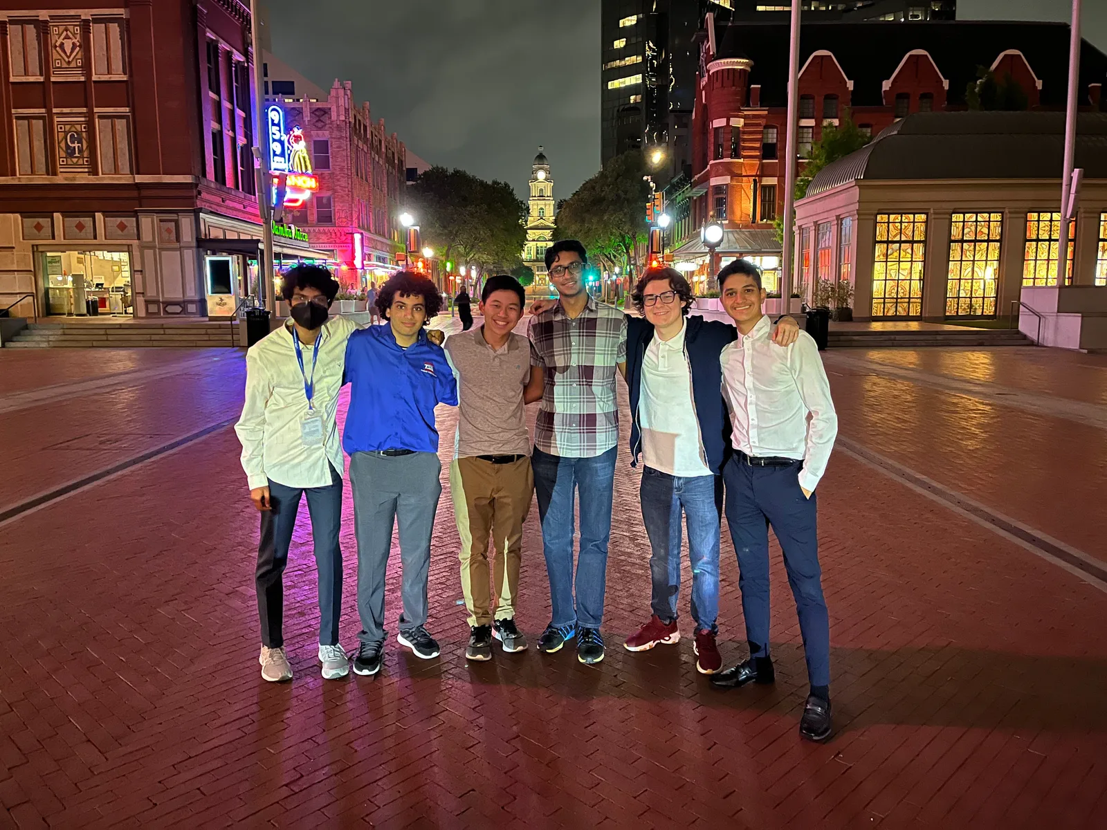 Members posing on a brick street in downtown Fort Worth at night