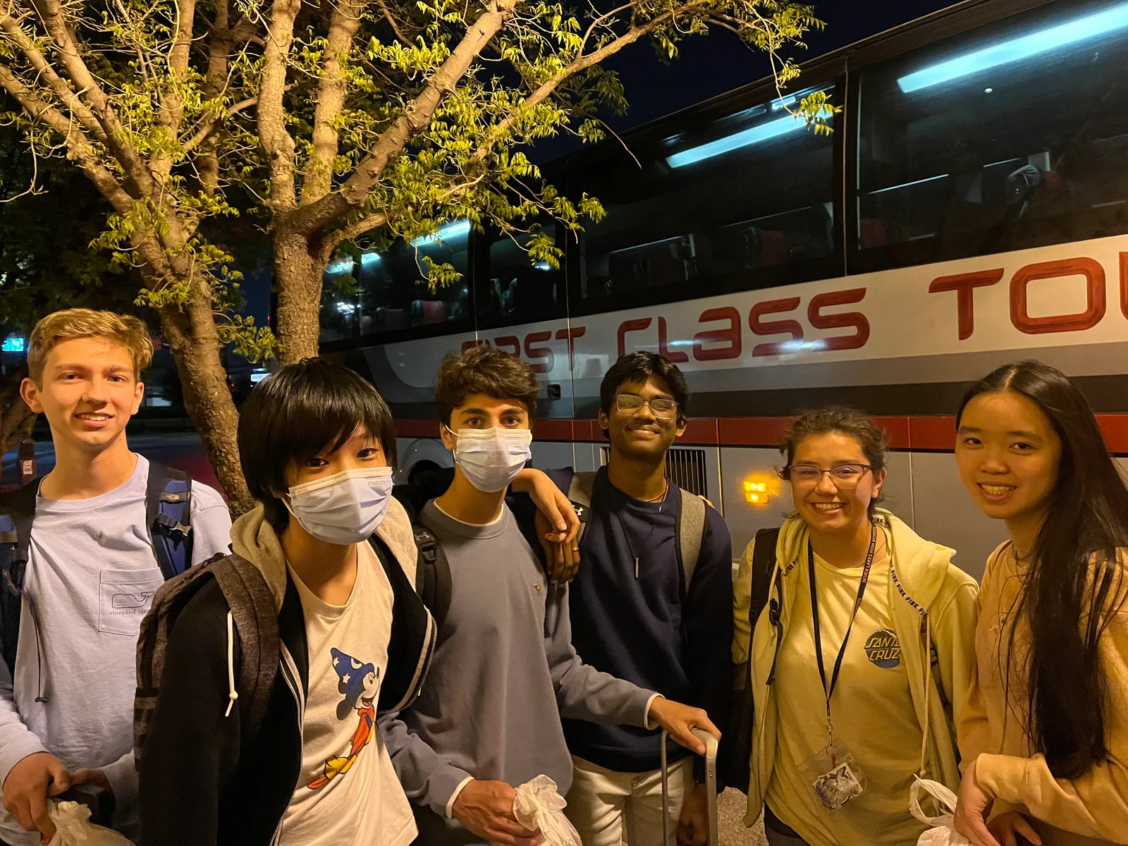 Members unloading by the charter bus at night