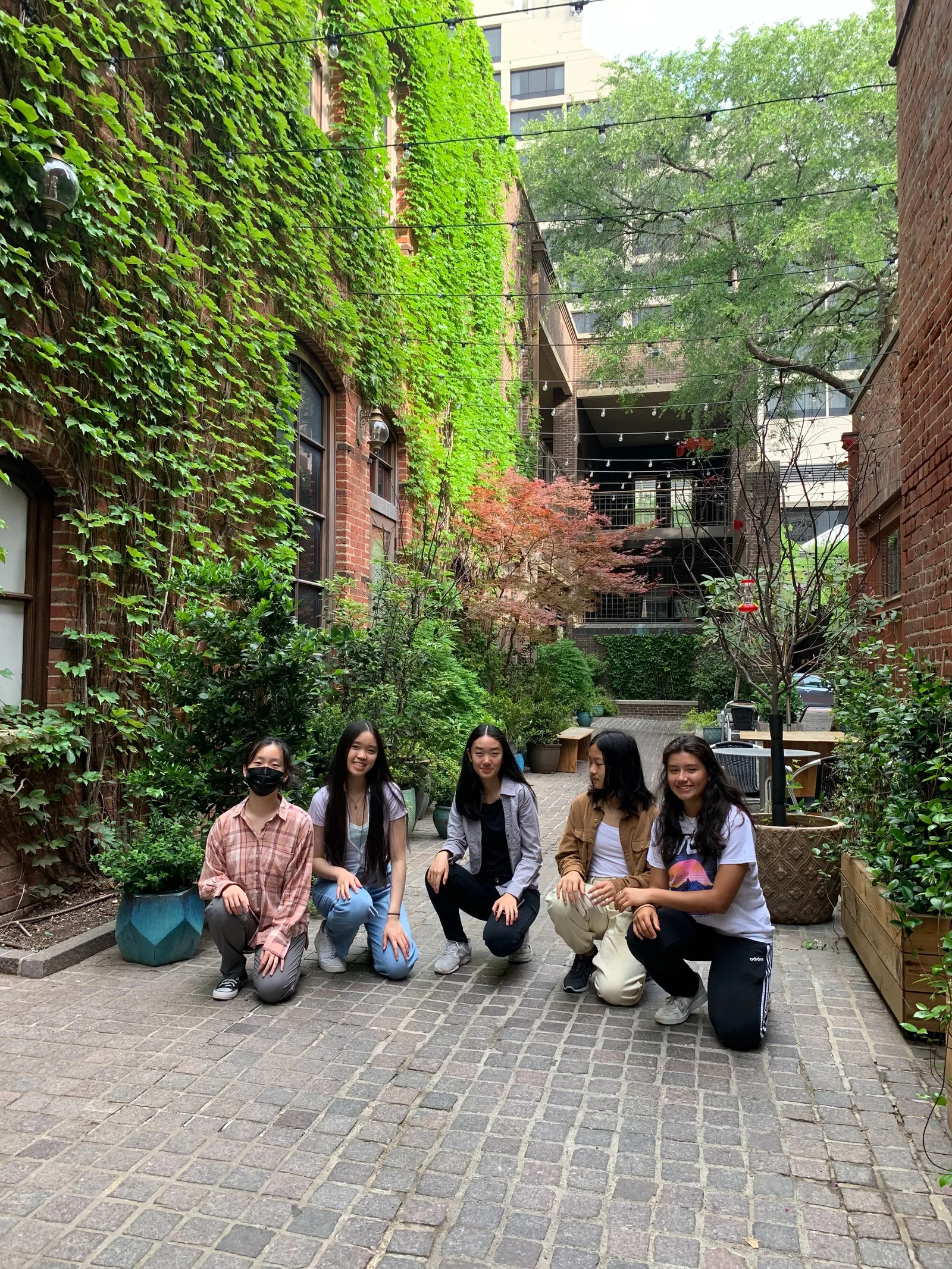 Members kneeling in an ivy-covered courtyard
