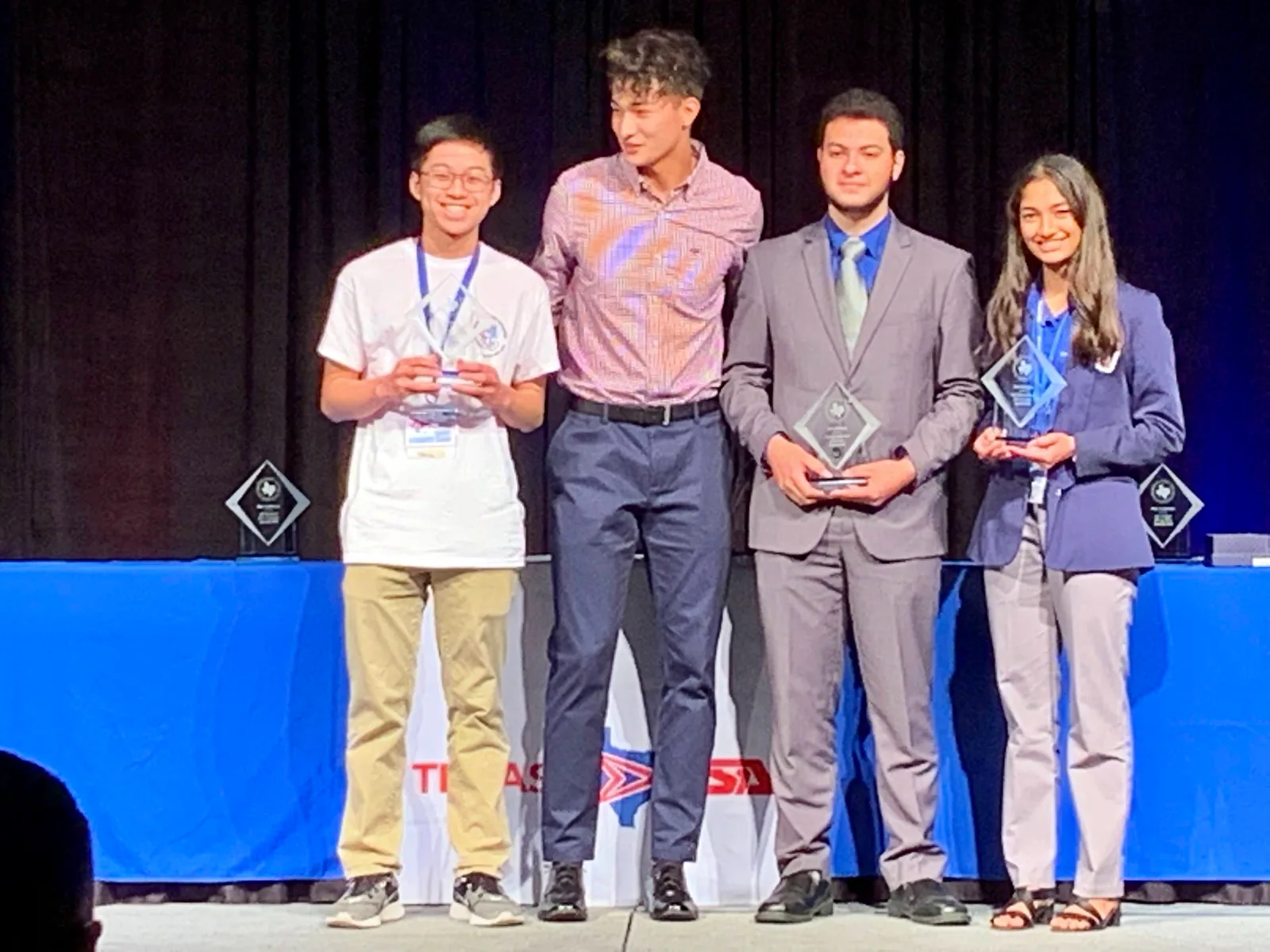 Members holding their awards on the State stage
