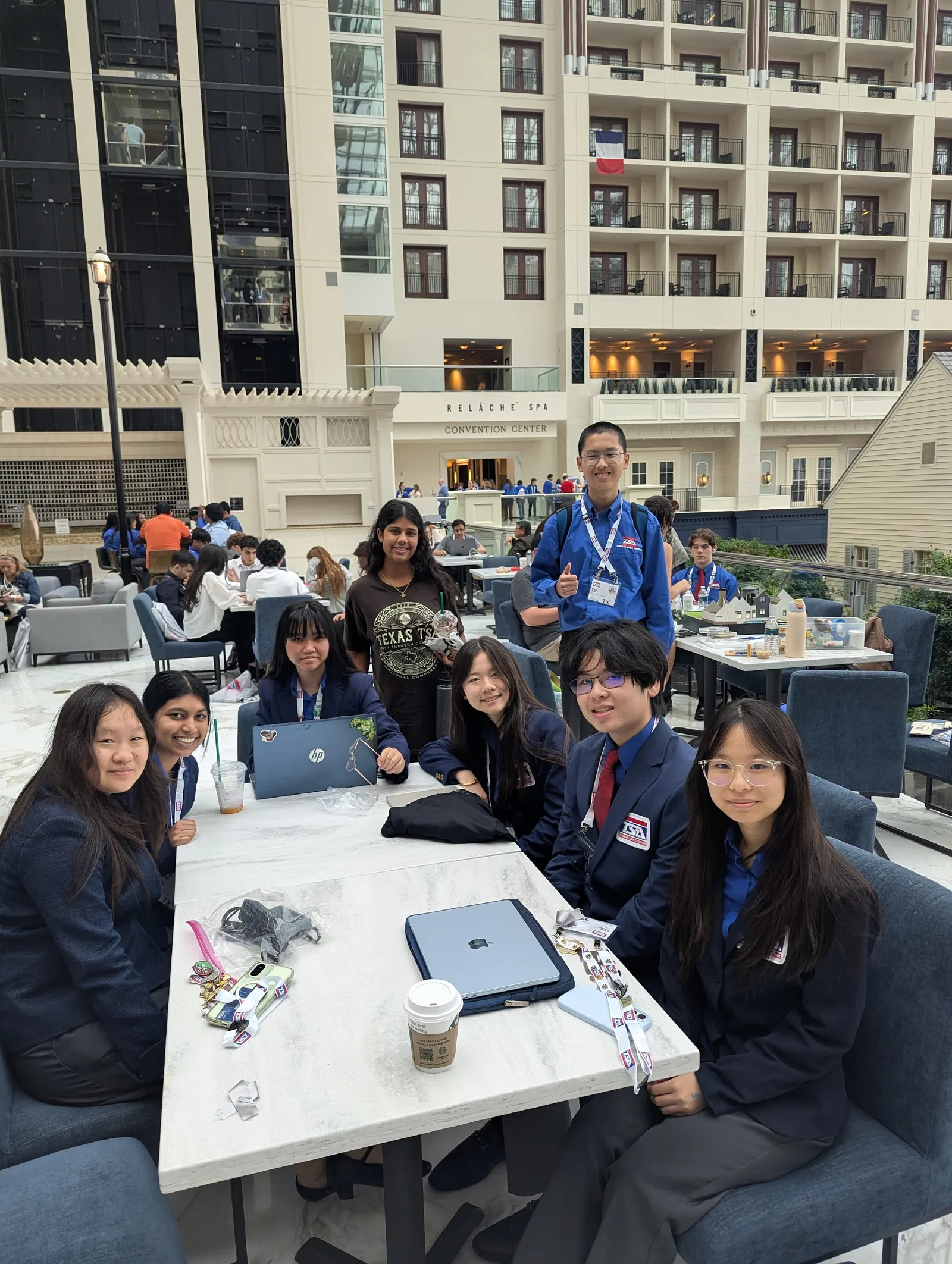 Members in competition attire prepping at a table in the Gaylord National atrium during the national conference