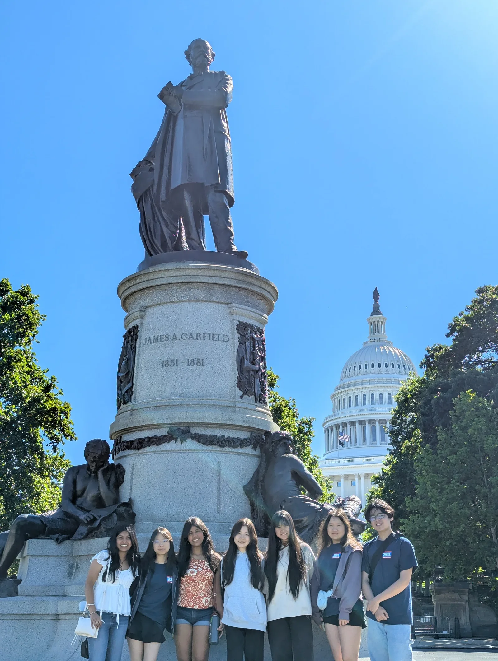 Members pose at the James A. Garfield Monument with the U.S. Capitol dome behind them
