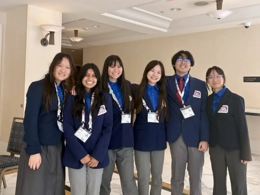 Six SLHS TSA members in navy competition blazers lined up together in the hotel lobby at the 2026 National TSA Conference
