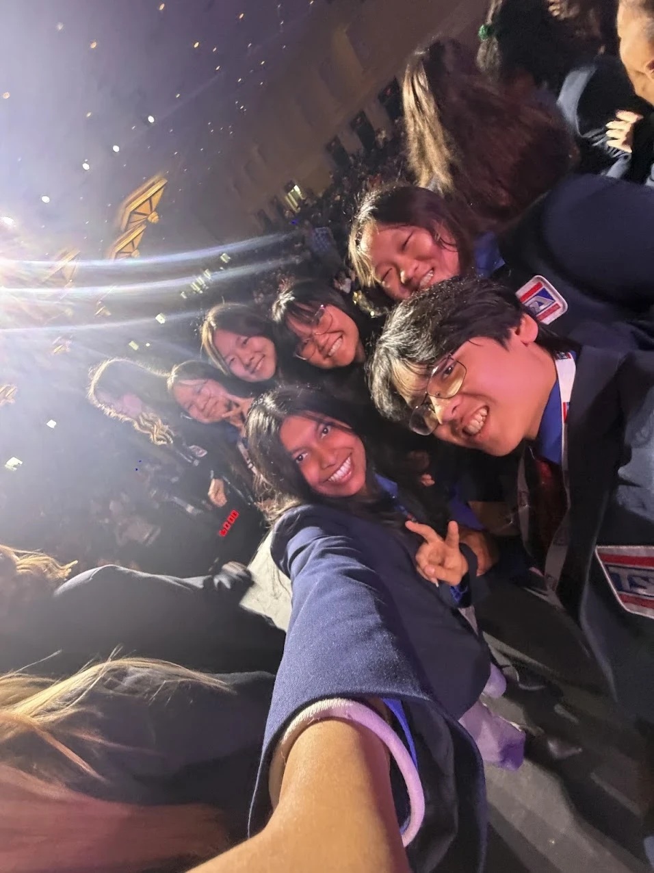 SLHS TSA members leaning in for a tilted group selfie during an evening session at the 2026 National TSA Conference, stage lights and confetti behind them