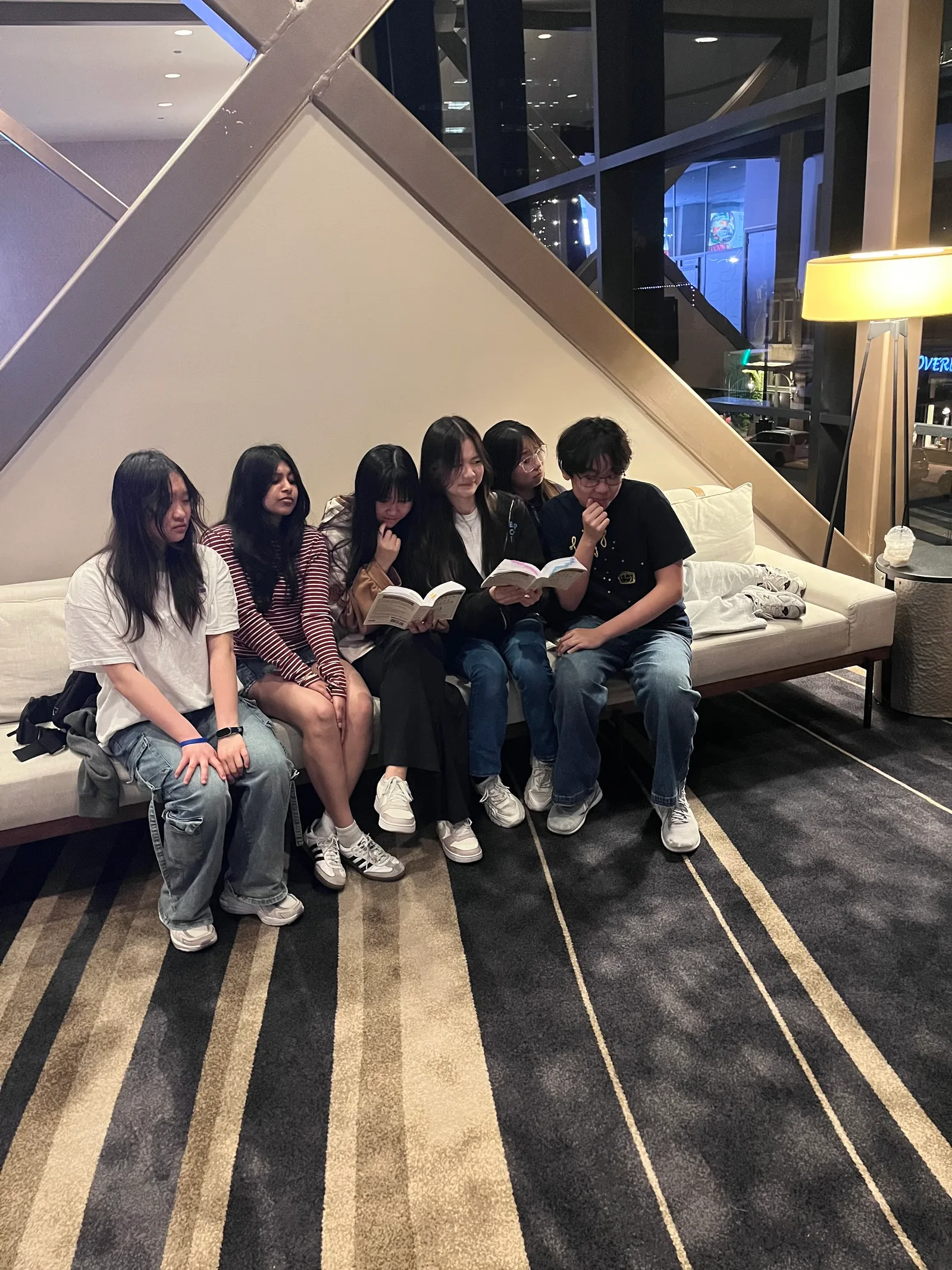 Six members winding down together on a bench in the hotel lobby at night
