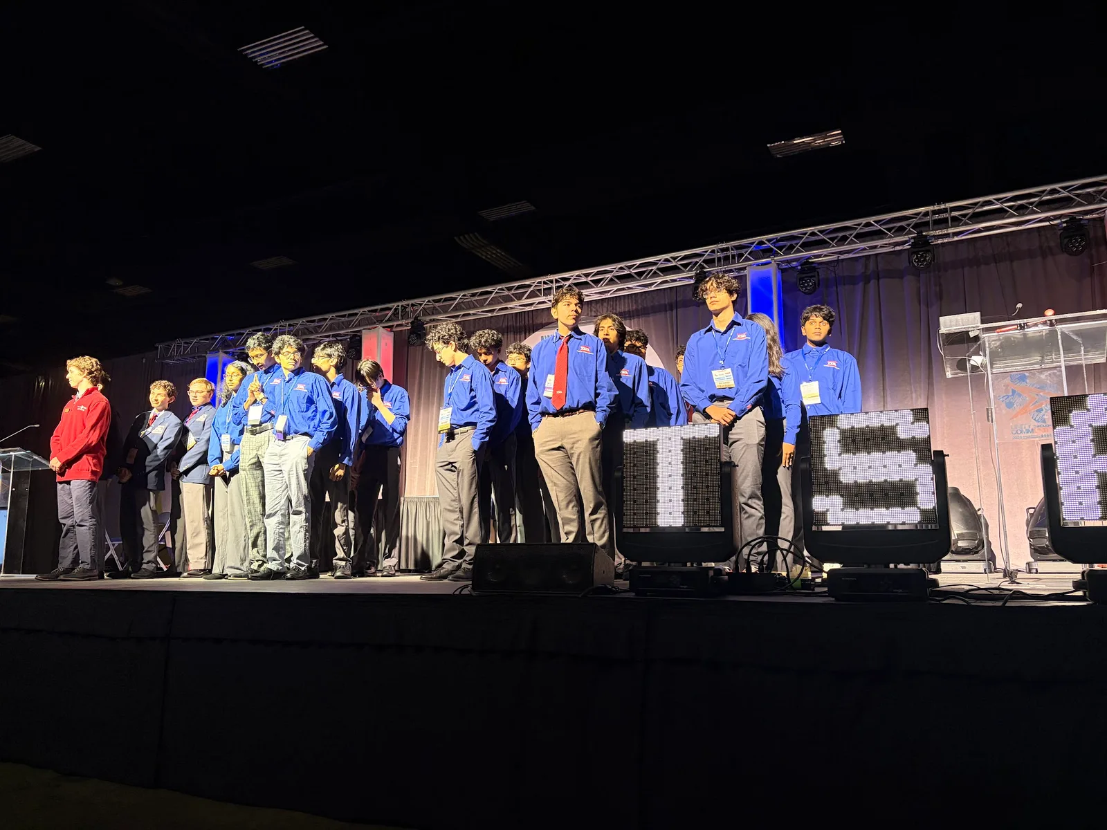 SLHS TSA competitors lined up on the awards stage behind lit TSA letters at the 2026 Texas TSA State Conference
