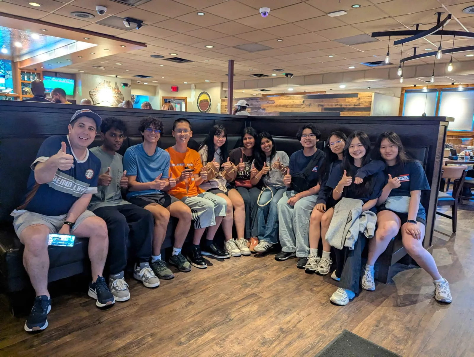 Members and advisor giving thumbs-up at a restaurant social
